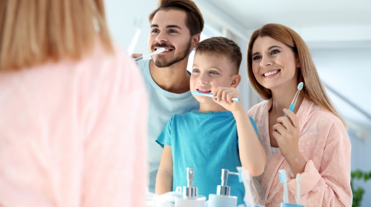 Smiling family brushing teeth together to prevent cavities in kids – On Q Dentistry